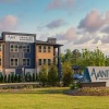 Exterior view of Avant at Midlothian, a modern apartment community featuring a three-story building with contemporary finishes, surrounded by greenery and a large monument sign at the entrance.